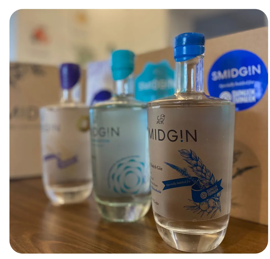 Three Smidgin bottles with personalised labels and coloured wax caps, beside a branded gift box